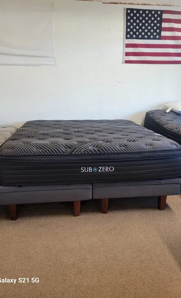 Mattress on bed frame in a bedroom, with a U.S. flag hanging on the wall.