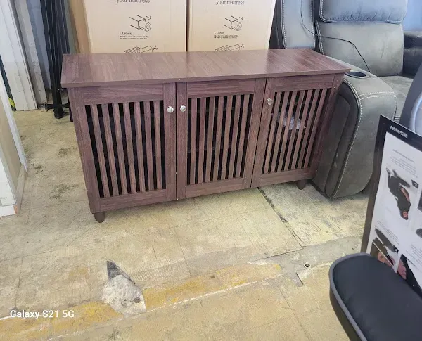 Brown slatted wooden cabinet with drawers, stored in a cluttered room with boxes and a chair nearby