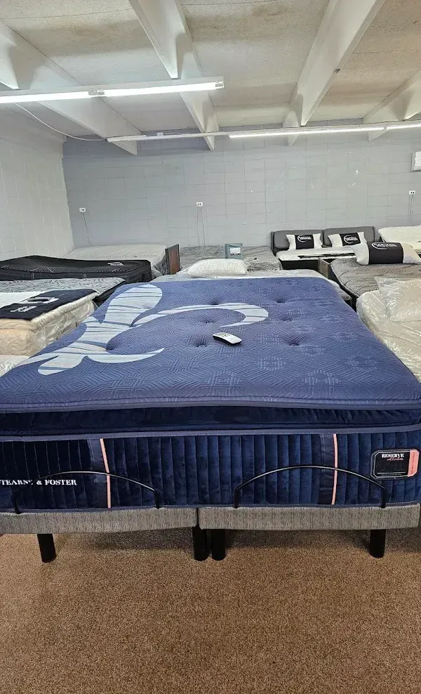 Mattress showroom with a blue bed in the foreground and other beds lined up behind it.