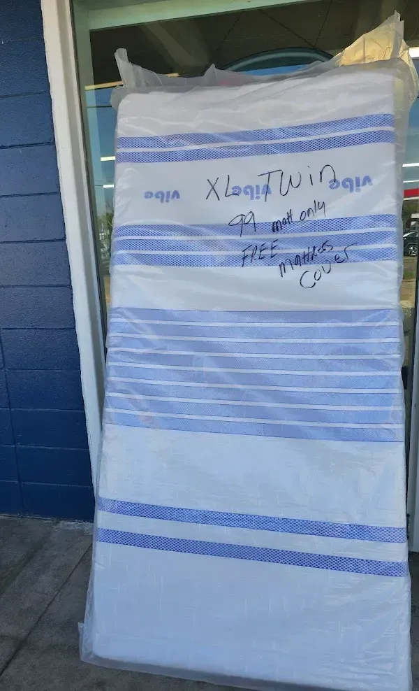 Tall white-and-blue striped mattress leaning against a blue wall, with handwritten text on the top.