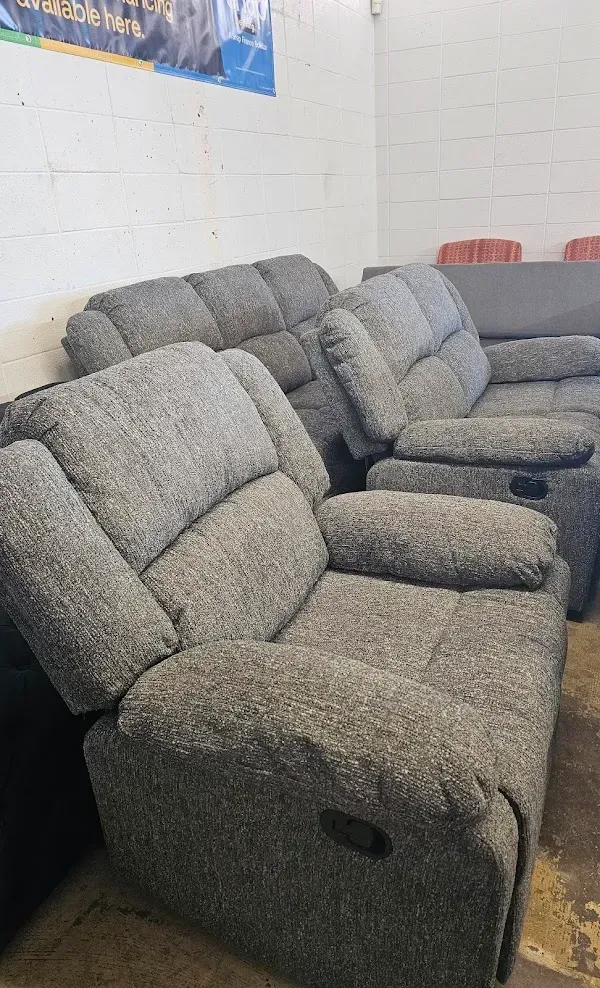 Gray reclining sofa and loveseat in a room with white brick walls.