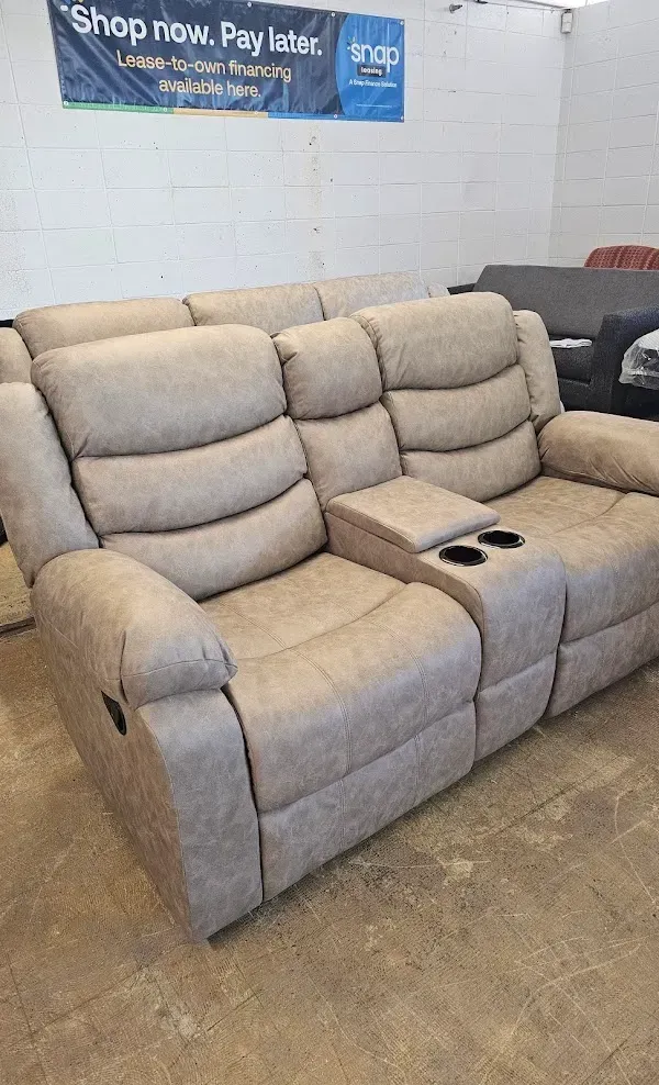 Beige reclining loveseat with center console in a furniture showroom