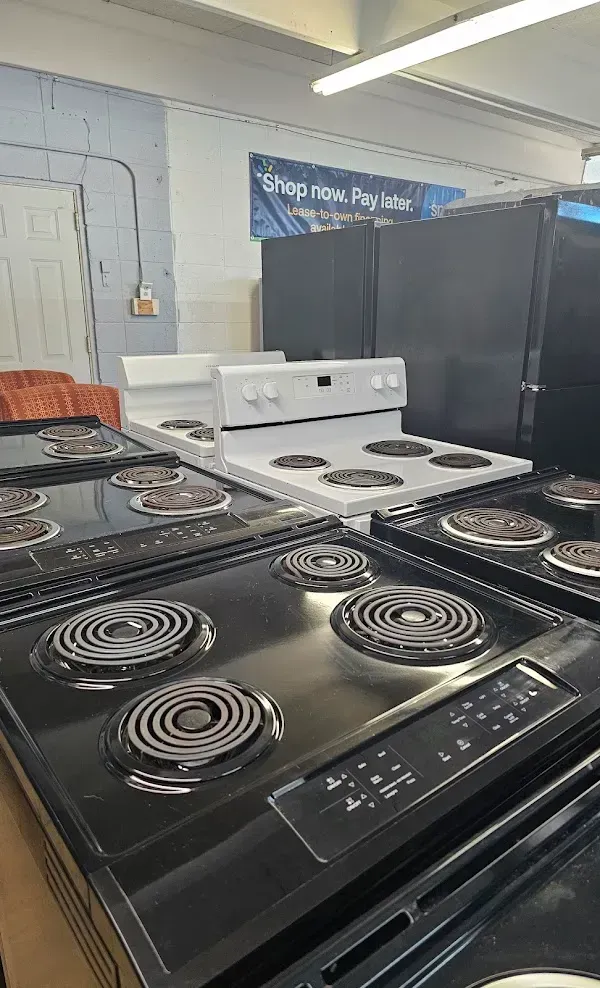 Rows of electric stoves in a showroom, with black and white ranges in the foreground