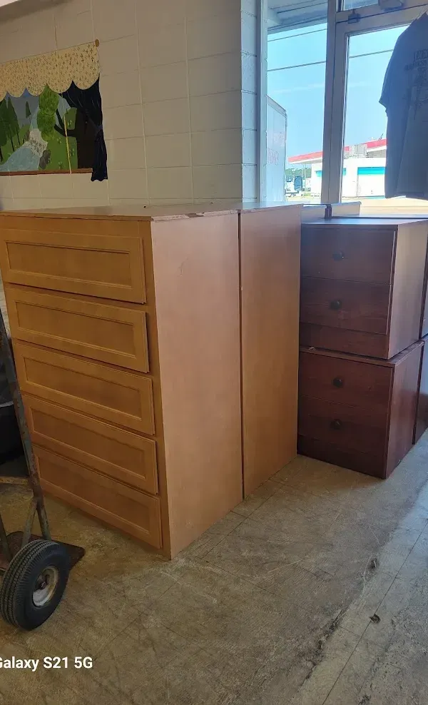 Wooden dresser and cabinet in a room with tiled walls and a window