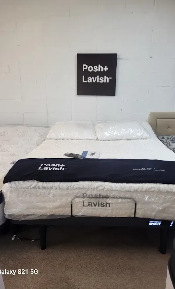 Bedroom with a white bed, black Posh+Lavish sign, and mattress cover.