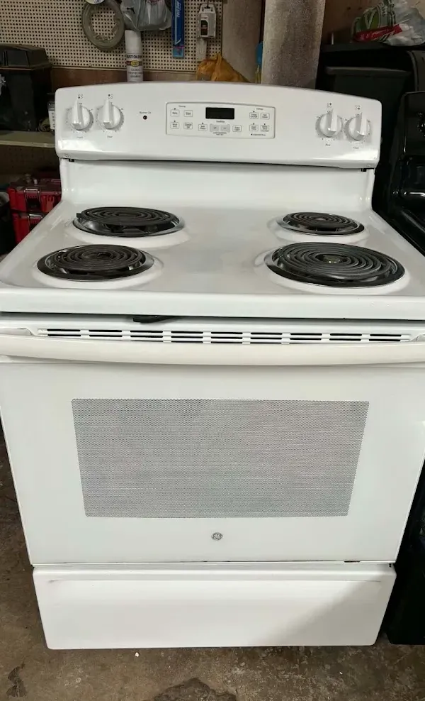 White electric stove with four coil burners and oven, front view indoors.