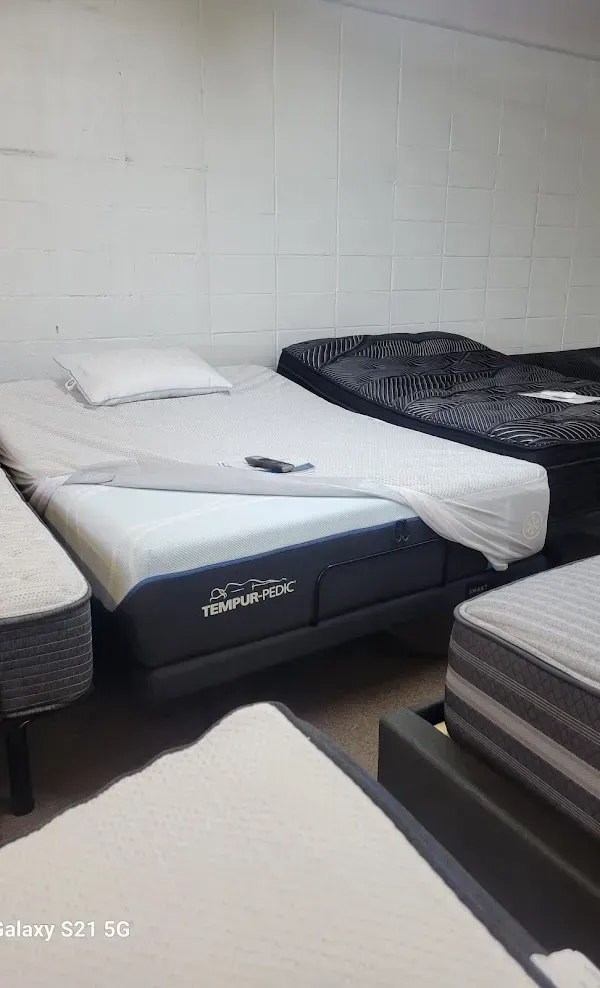 Small bedroom with three single beds, white bedding, and a plain white wall.