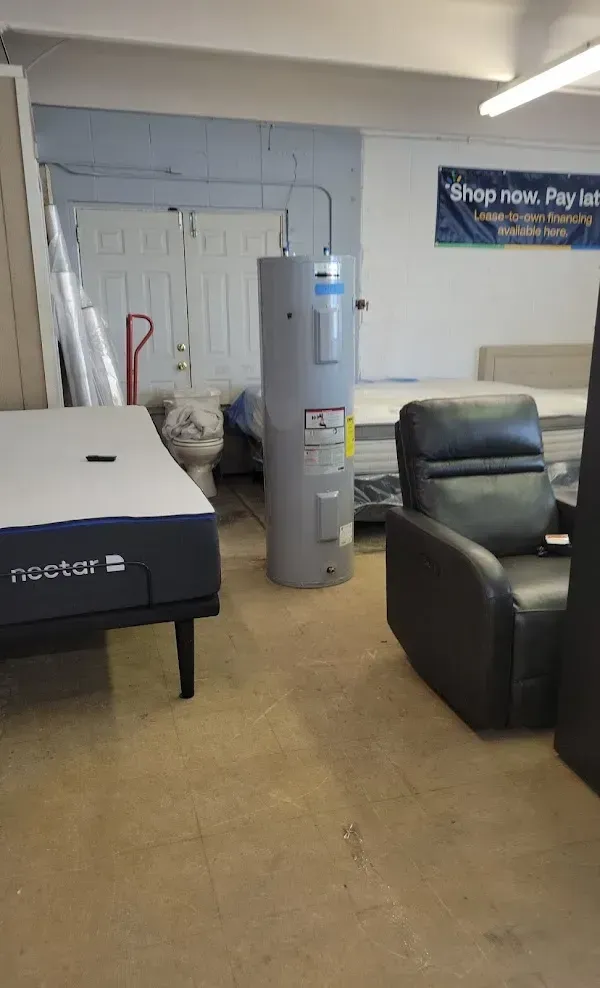 Waiting room with a black exam table, gray water cooler, and black leather chair in a clinic interior.