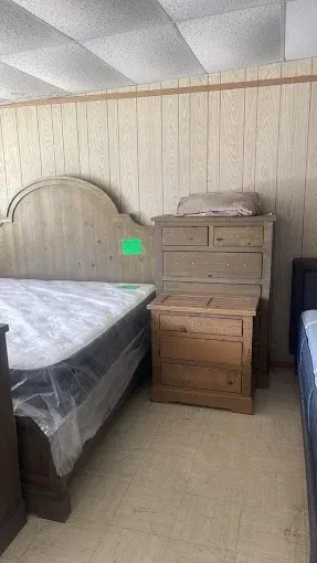 Bedroom with a bed, two wooden dressers, and a curved floor lamp beside a window.