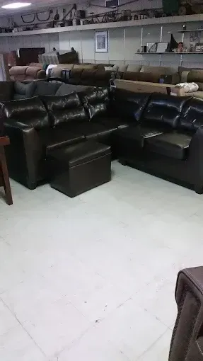 Black leather sectional sofa set in a furniture showroom with shelves and decor in the background