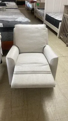 White upholstered armchair in a furniture showroom with beds and other furniture in the background