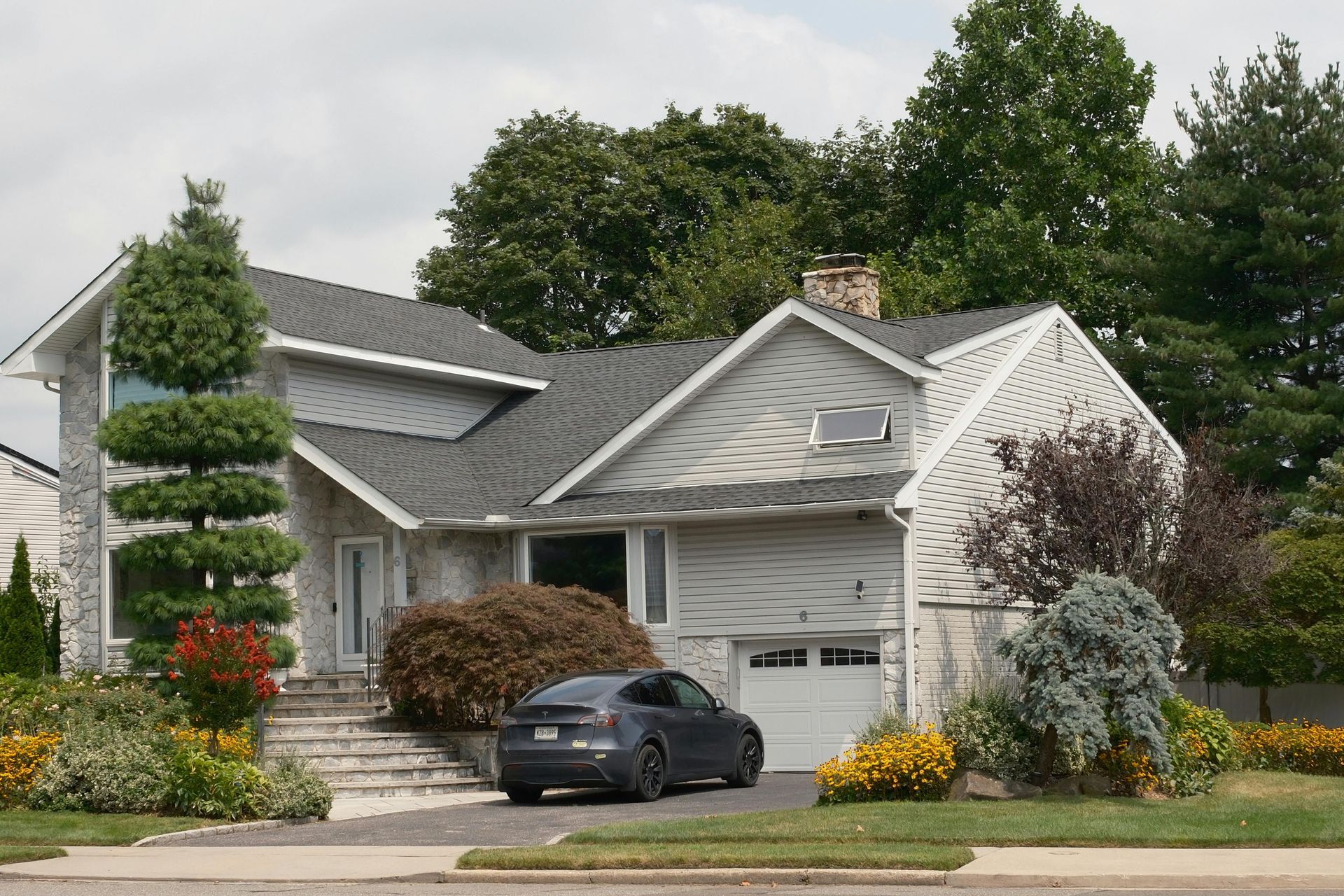 A car is parked in the driveway of a single family home.