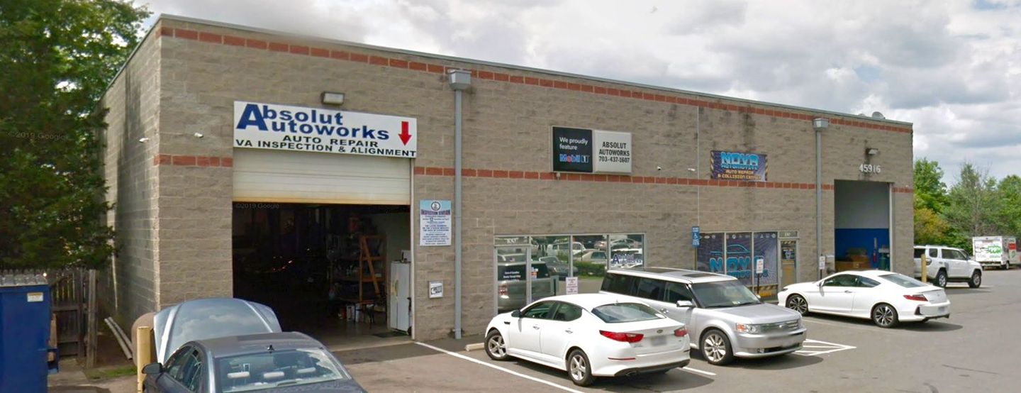 A row of cars are parked in front of a brick building.
