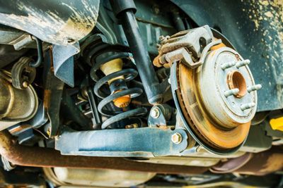 A close up of the underside of a car with a brake and shock absorber.