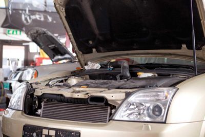 The hood of a car is open in a garage.