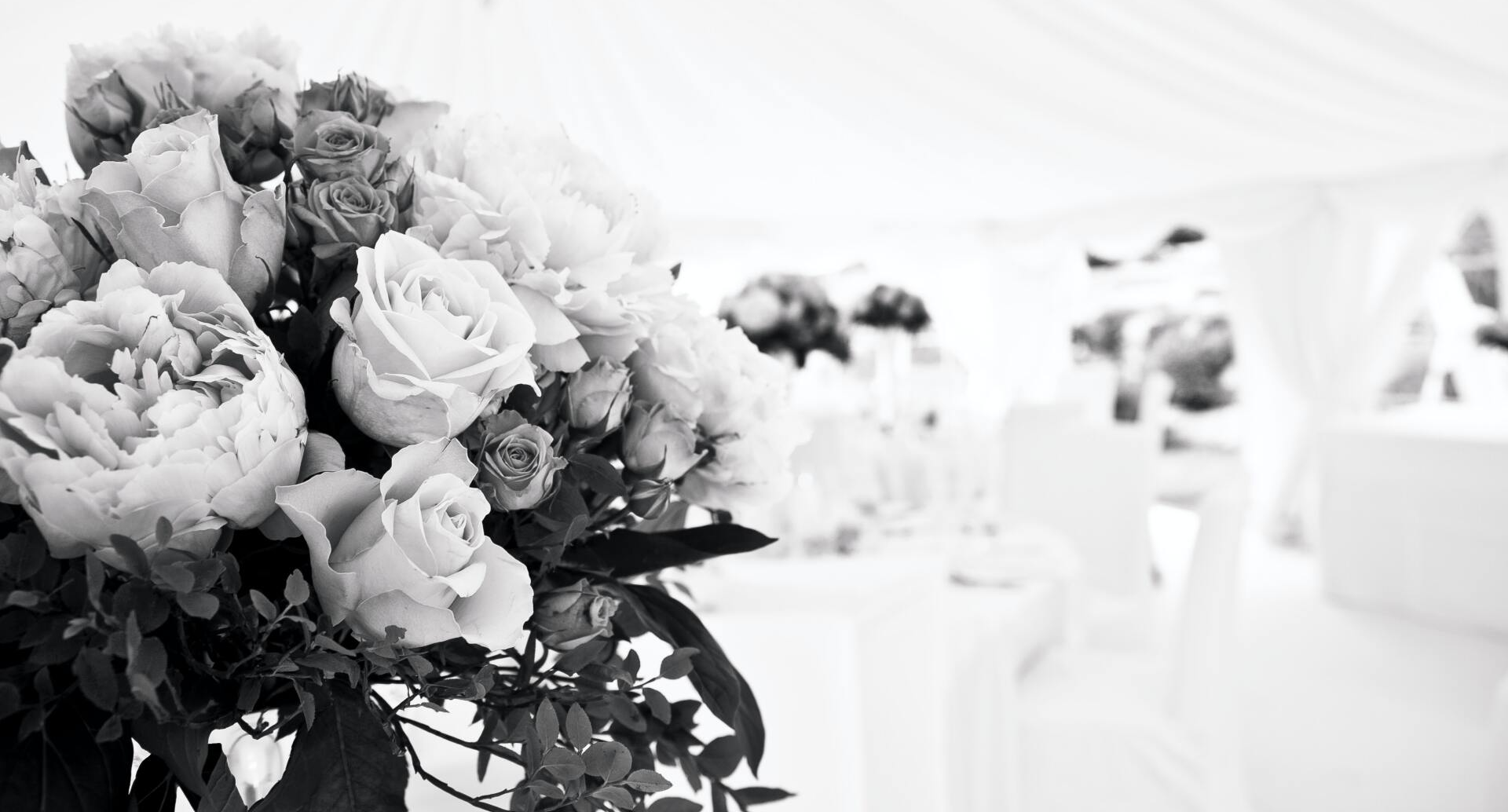 Photo en noir et blanc d'une composition florale, décor d'événement flou en arrière-plan.