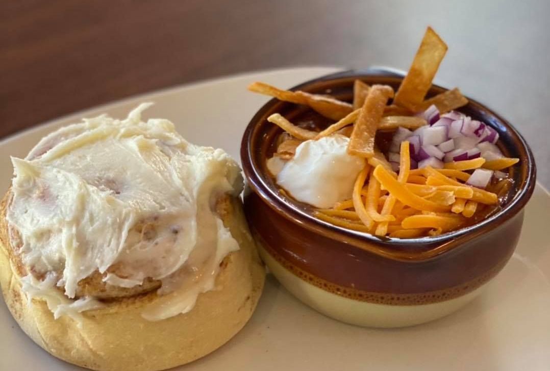 Image of a cinnamon roll and a bowl of chili. 