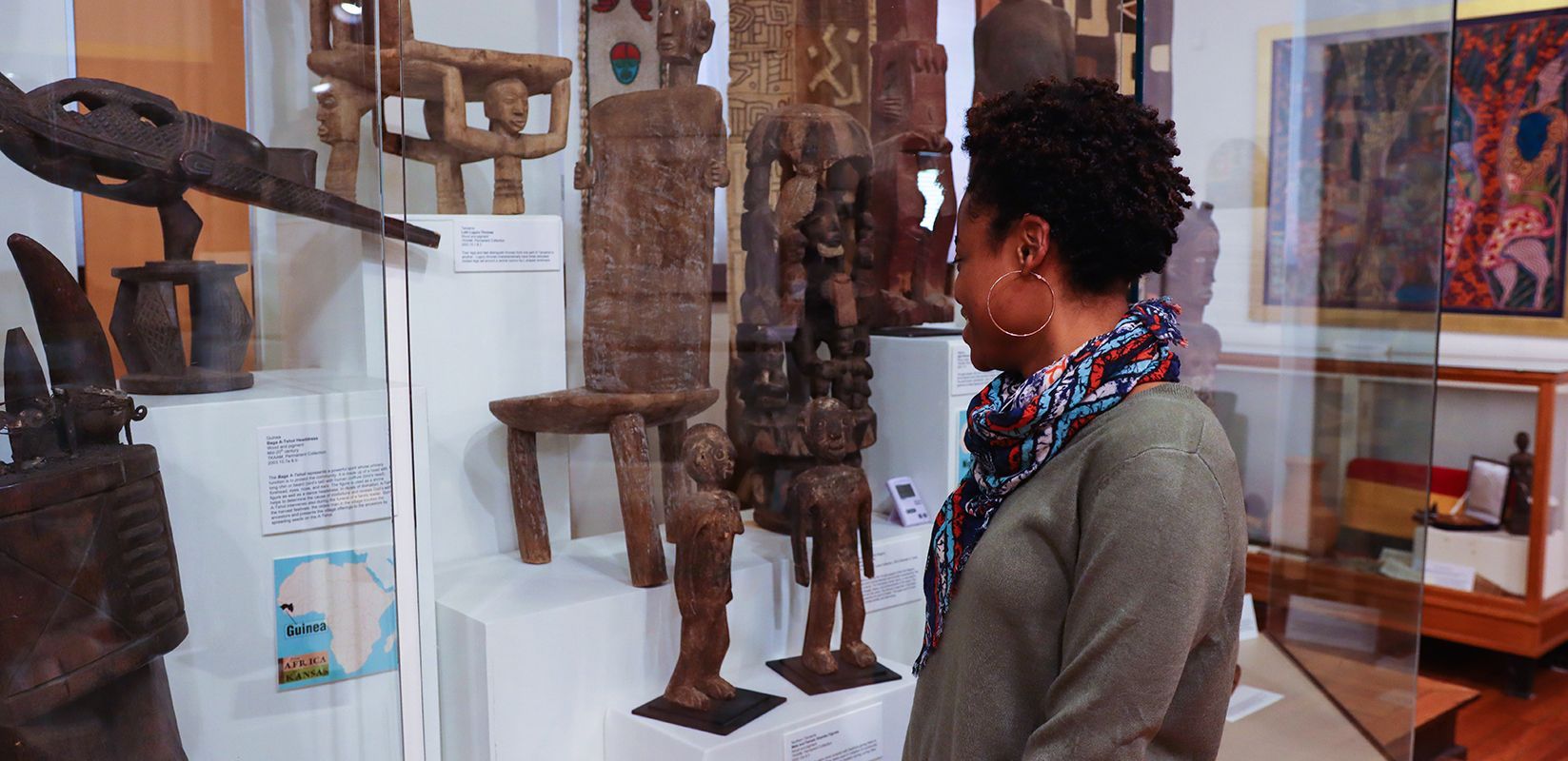 A person looks at wooden sculptures in a museum exhibit at the Kansas African American Museum.