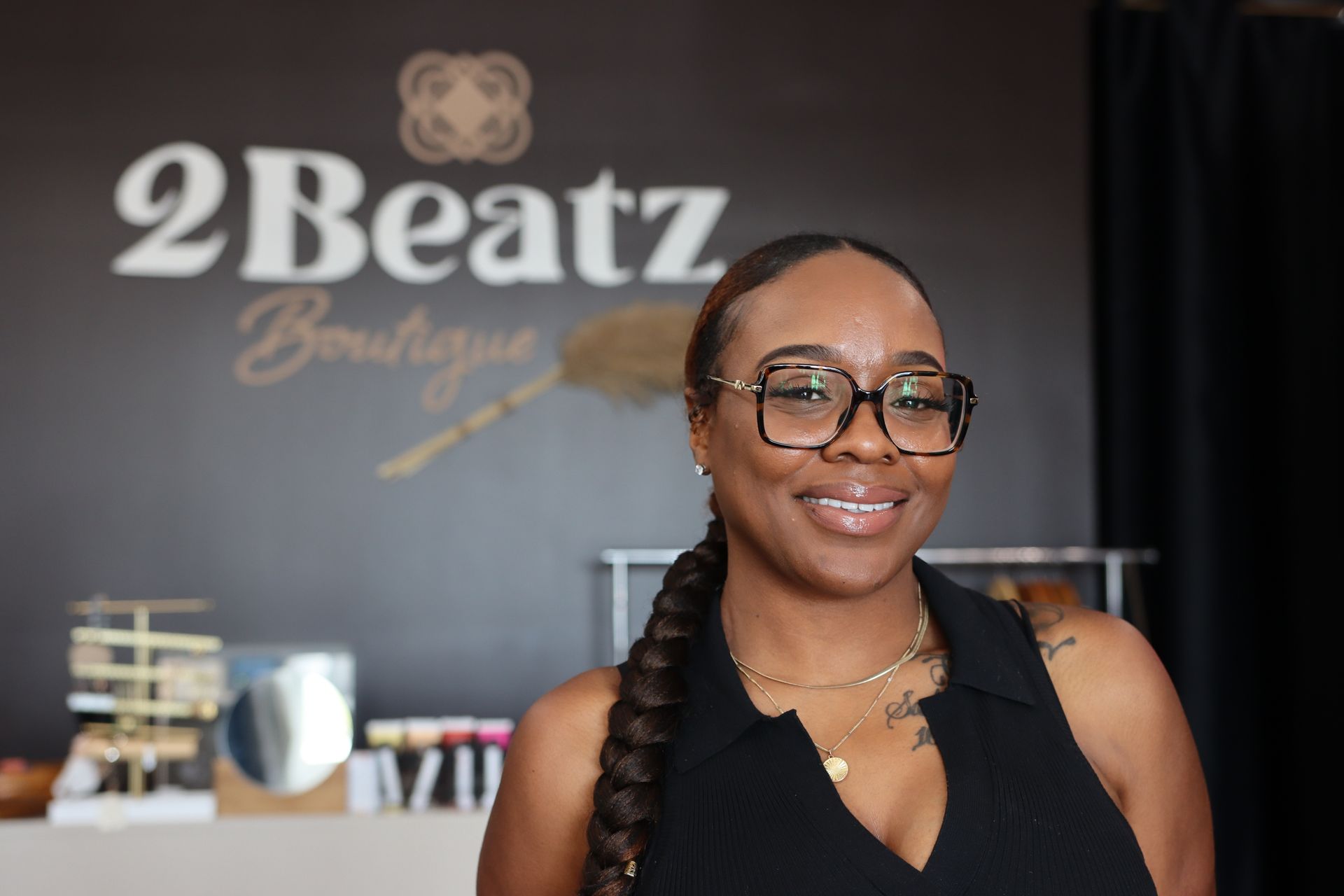 Smiling person wearing glasses stands in front of a 