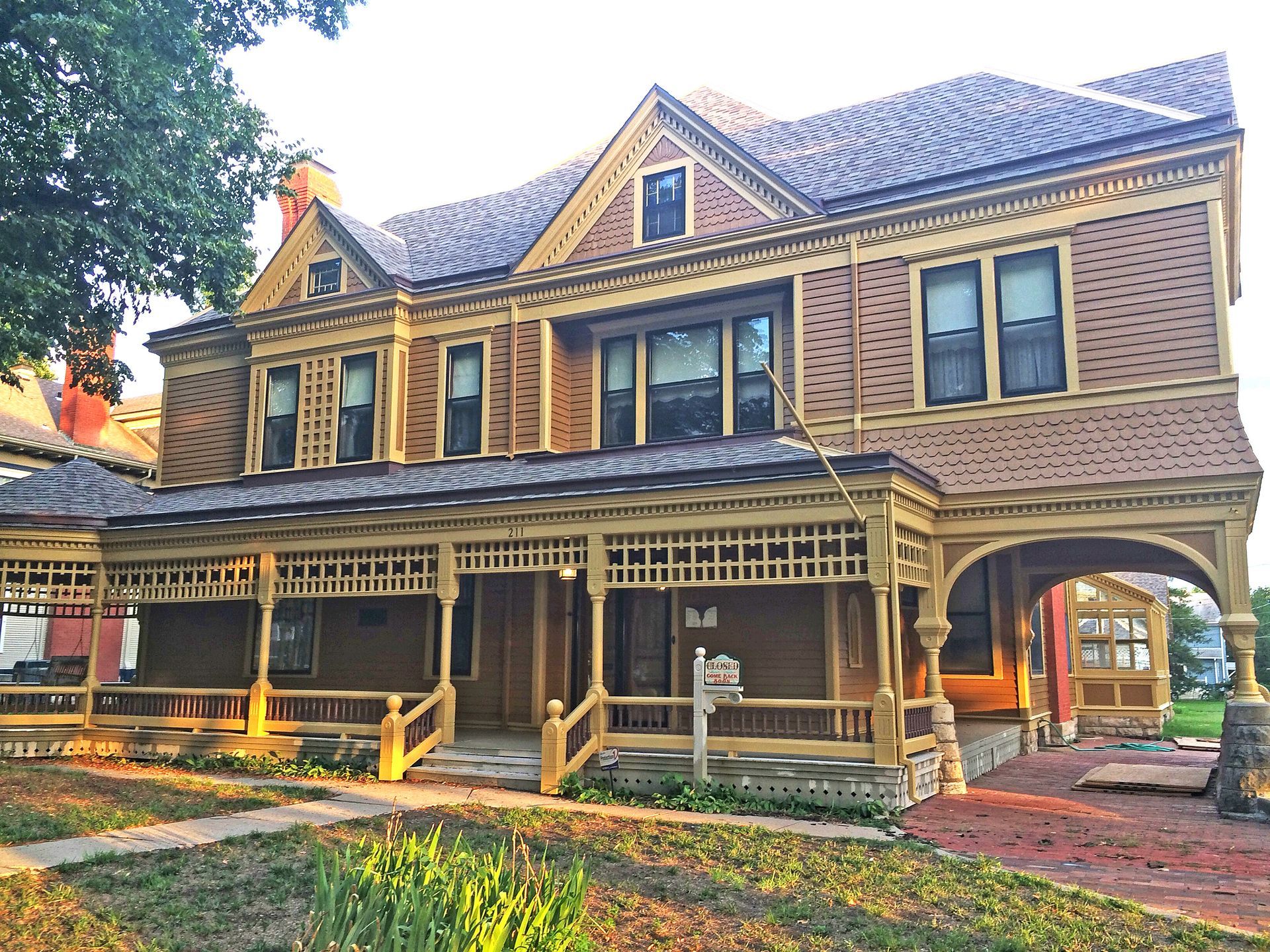 A large Victorian house with yellow trim, a wrap-around porch is the home of Warkinton Museum in Newton, Kansas