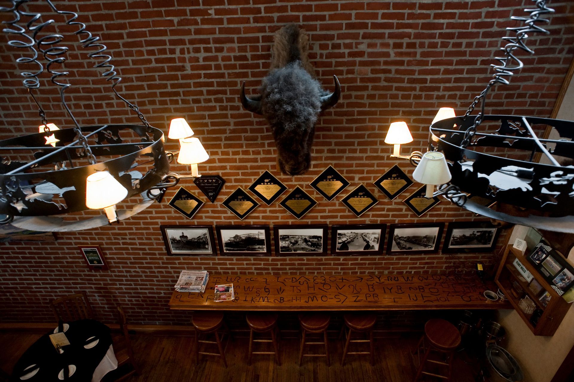 Rustic room featuring a buffalo head mount and wagon wheel chandeliers at the Grand Central Hotel in Cottonwood Falls.