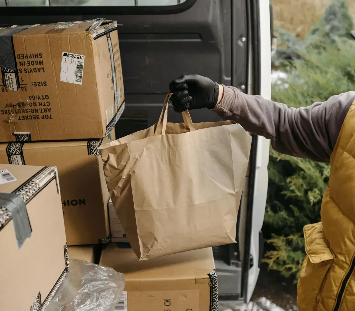 Person loading cardboard boxes and a paper bag into the back of a van