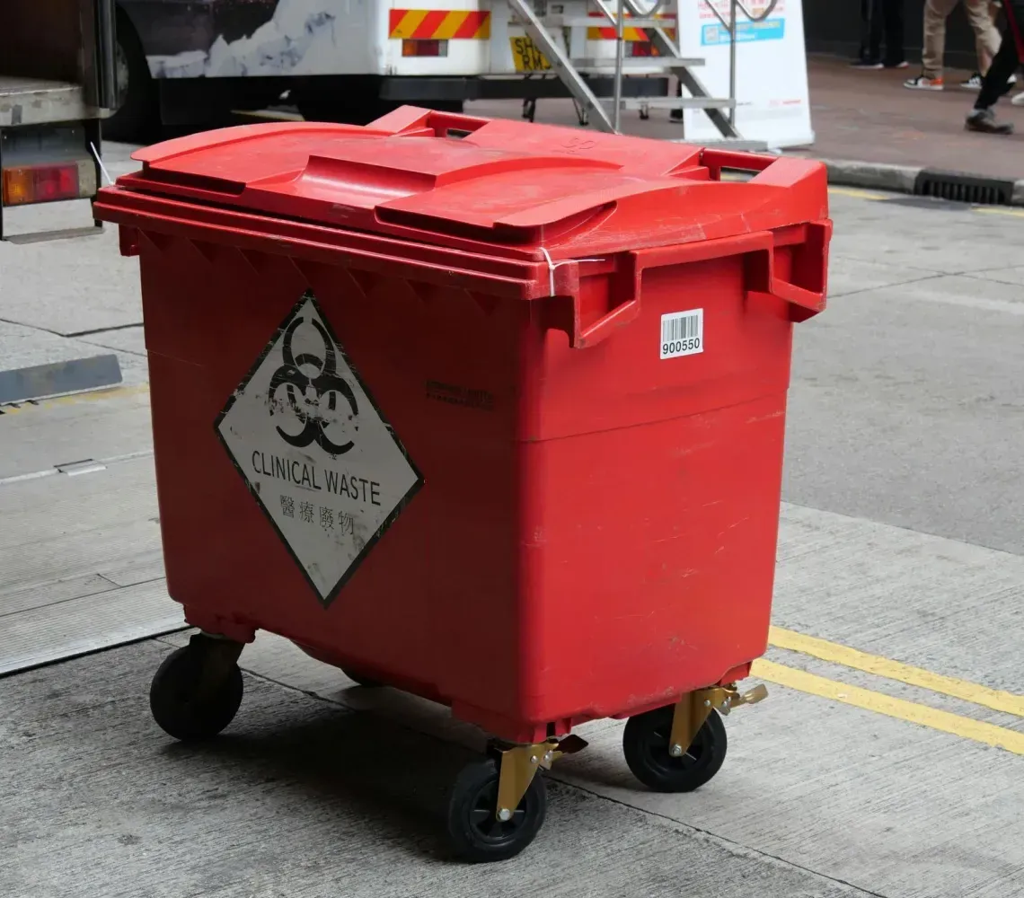Red biohazard waste bin on wheels on a city street