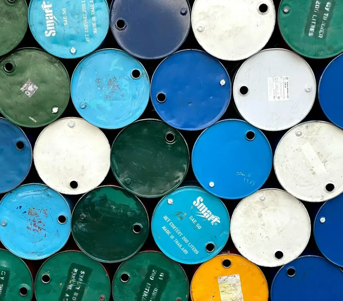 Stacked colorful metal barrels viewed from above, in blue, white, green, and yellow tones
