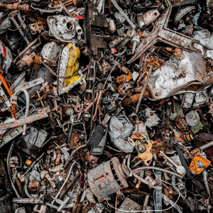 Pile of charred, broken metal and debris with ash and rust, filling the frame