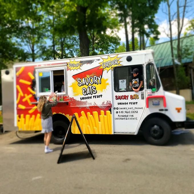 A woman is standing in front of a savory cuts food truck