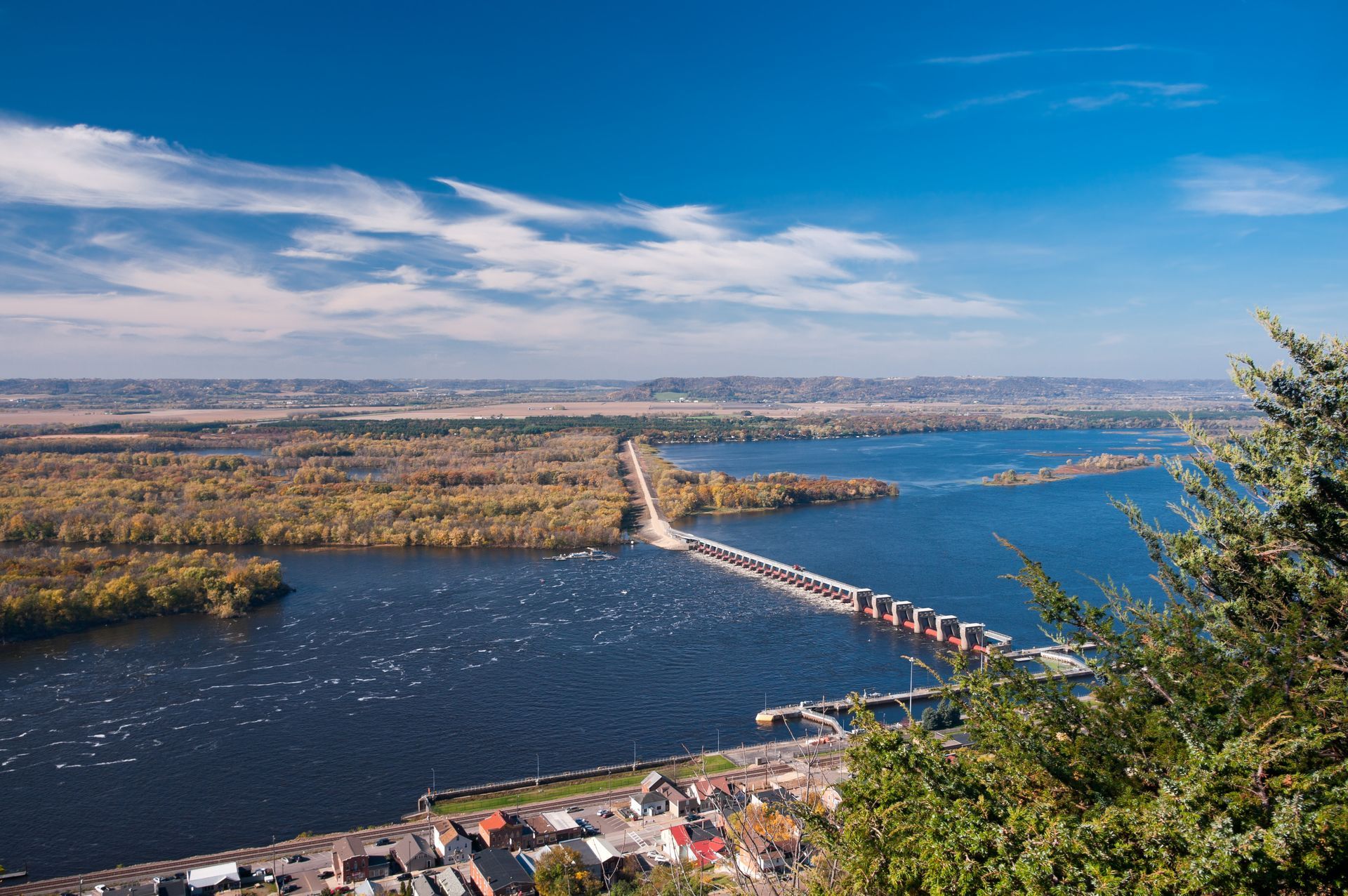Wide river with a long bridge crossing to a distant shoreline under a blue sky