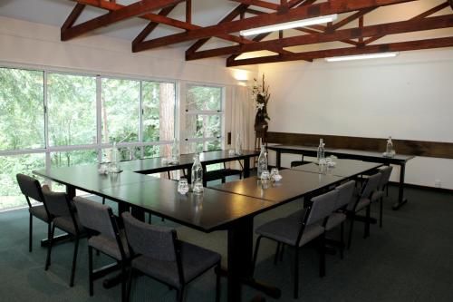 Modern conference room with large windows, long table, and black chairs under exposed wooden beams