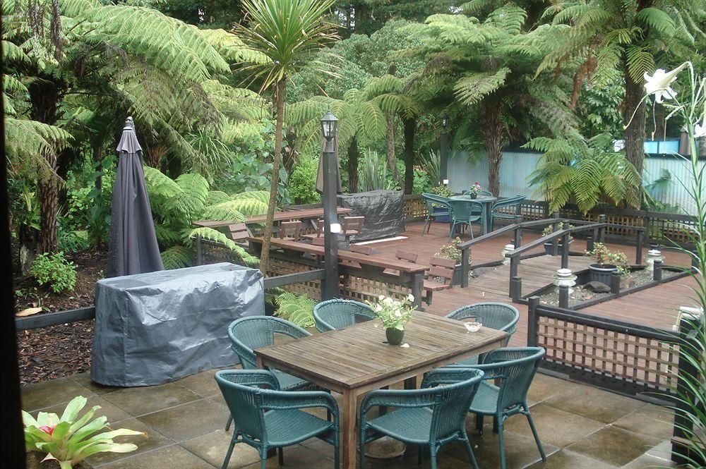 Patio garden with metal tables and chairs among lush palm trees and greenery