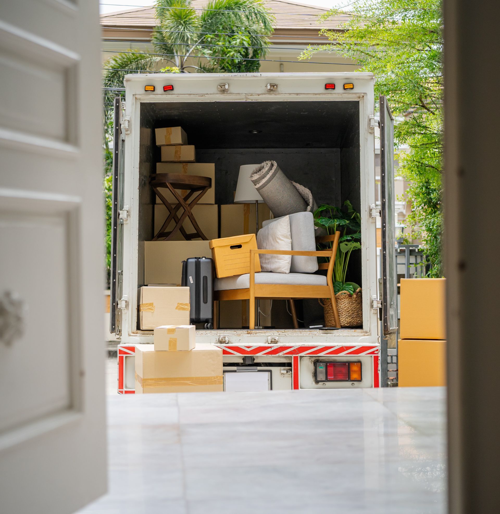Moving truck loaded with boxes and furniture at a home driveway.