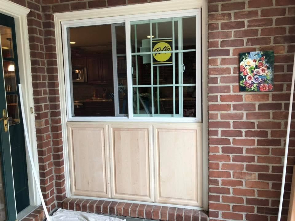 Brick exterior with window, security bars, and wooden panels below.