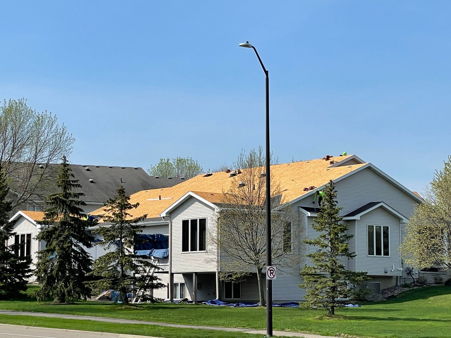 House with a partially removed roof under construction on a sunny day.  A streetlight stands in front.