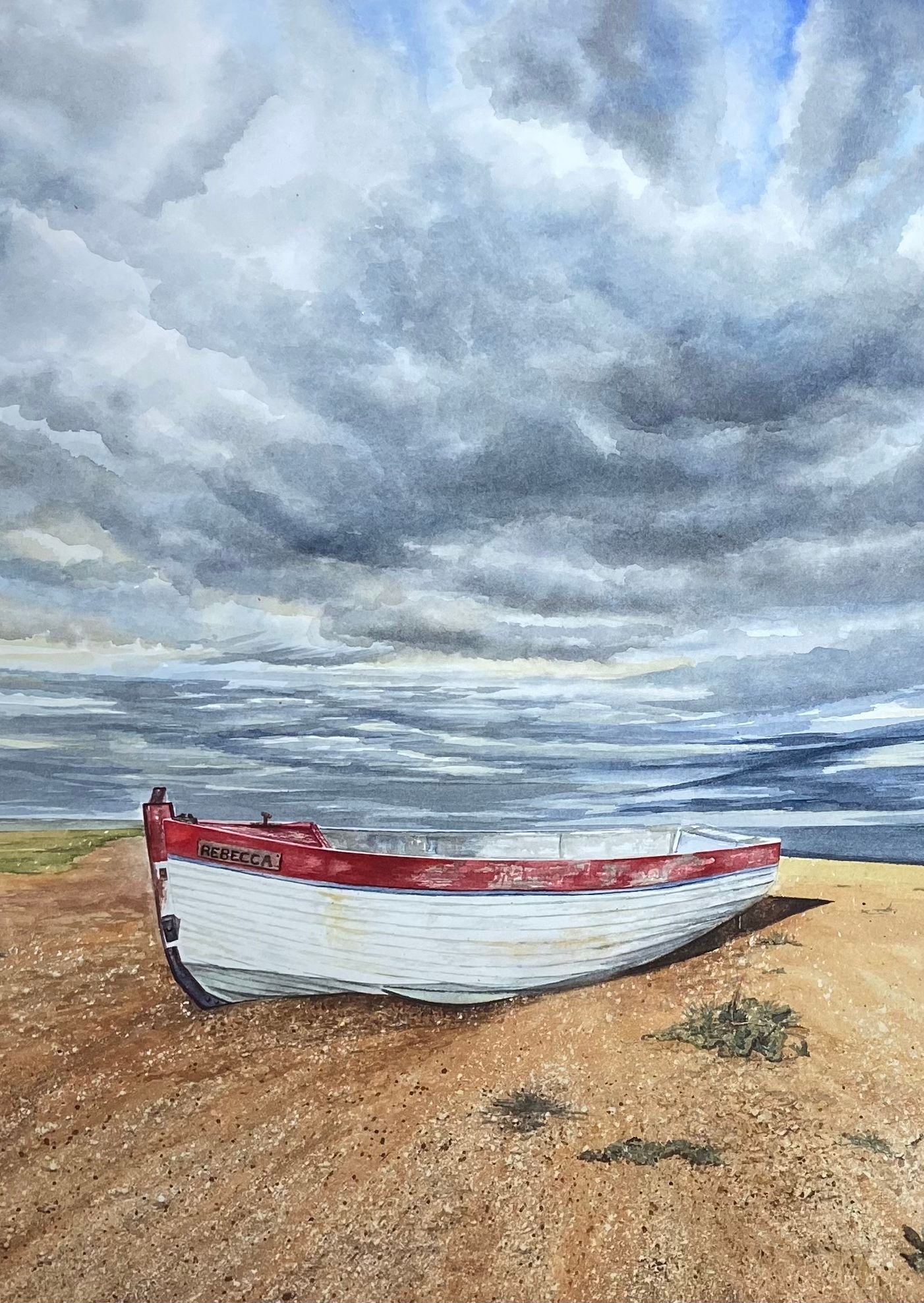 White and red boat on a sandy beach under a cloudy sky.