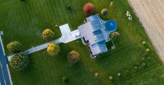 An aerial view of a house surrounded by trees and grass.