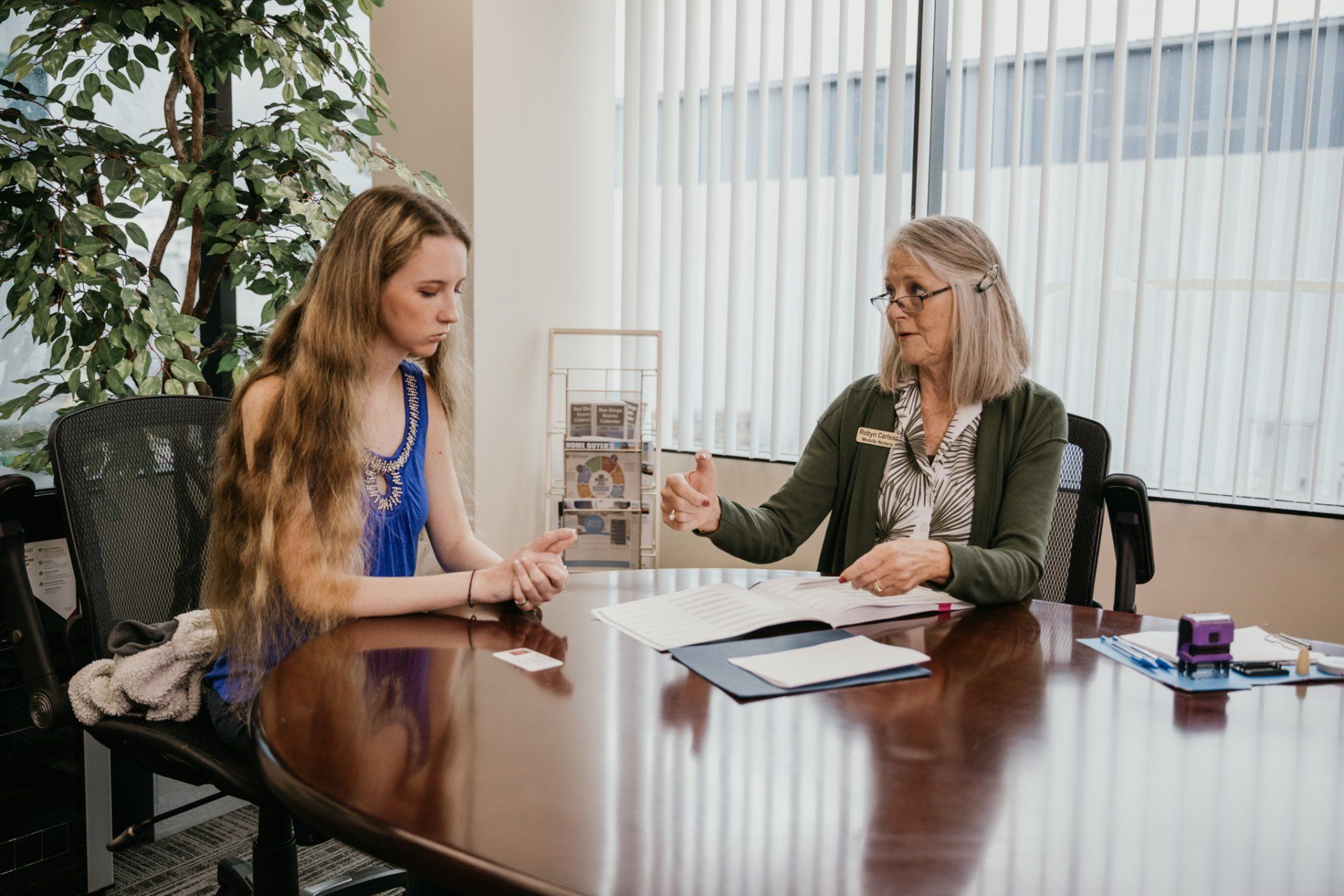 Two women talking across a conference table in a bright office