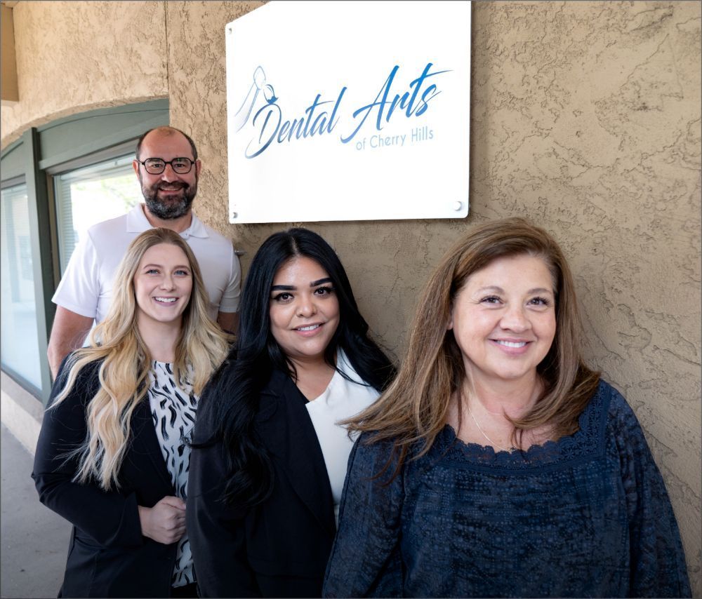 Group of dental staff posing in front of their office sign.