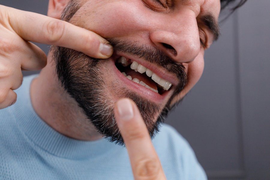 Man pointing to missing tooth, showing discomfort.