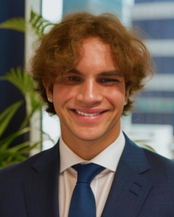 A young man in a suit and tie smiles for the camera