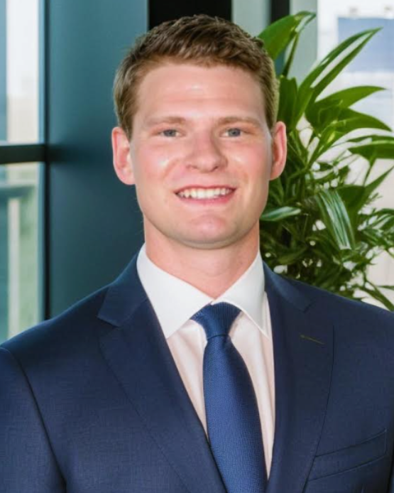 A man in a suit and tie is smiling in front of a window