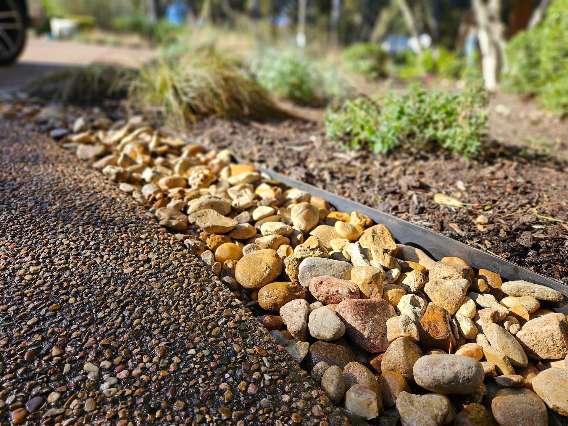 A row of rocks on the side of a road next to a metal edging.