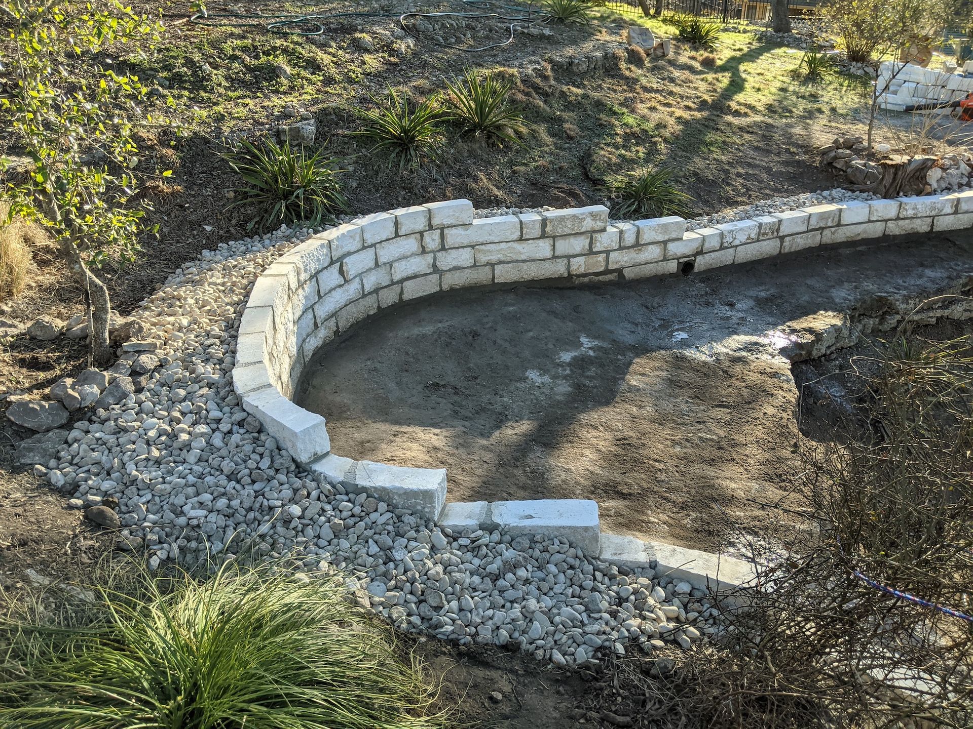 A brick wall is being built in the middle of a dirt field.