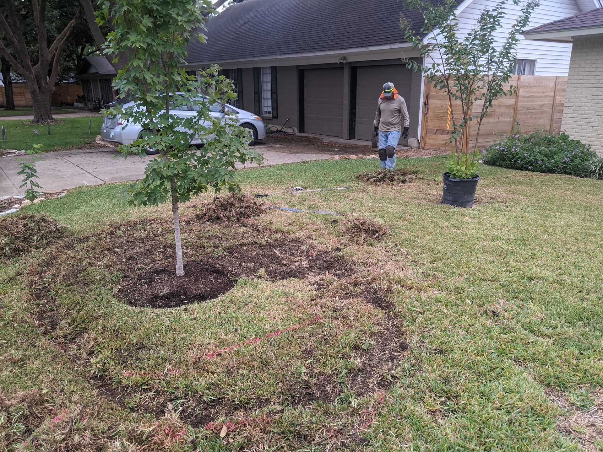 A woman is walking through a lush green lawn in front of a house.