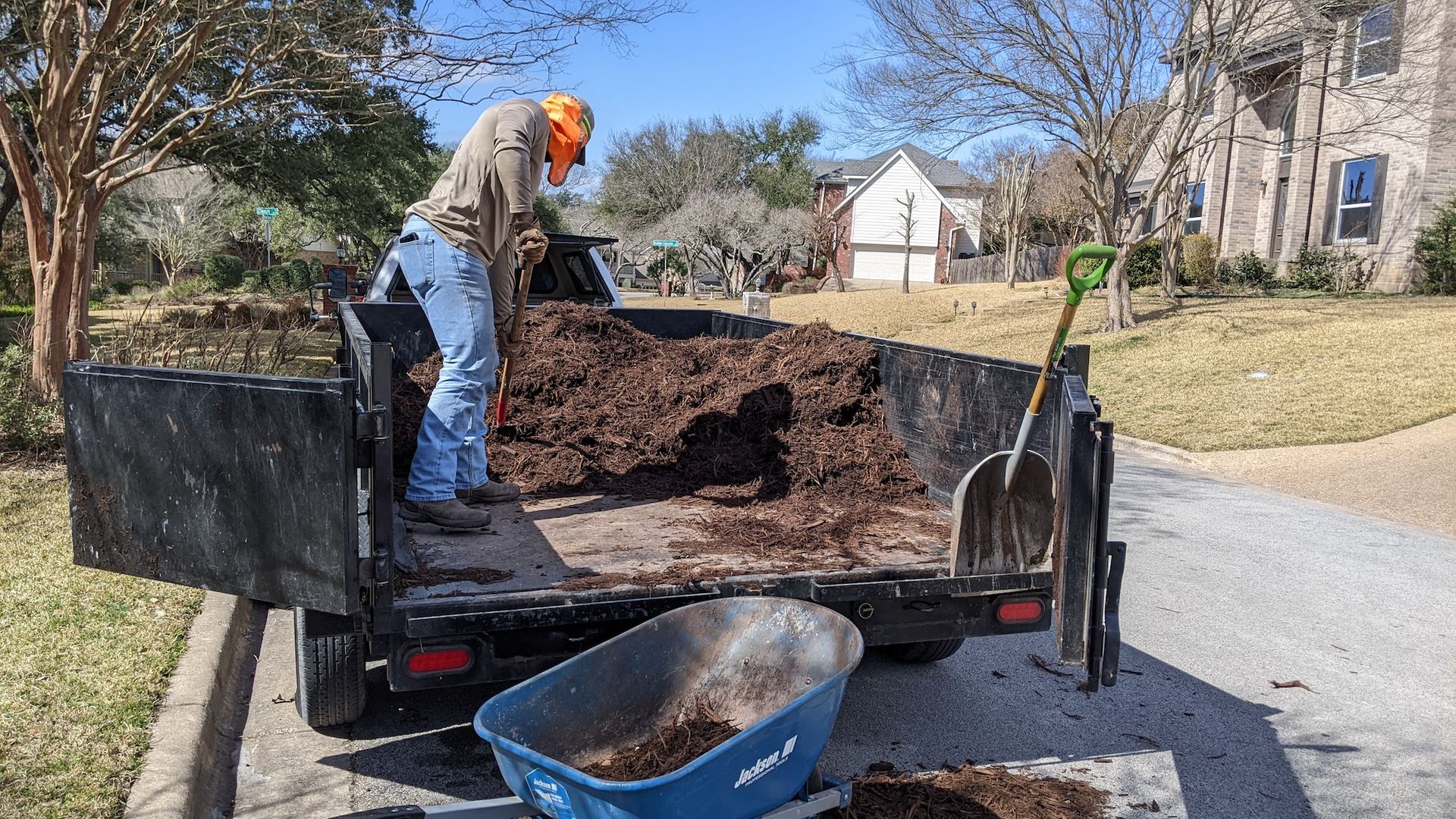 A man is loading dirt into a trailer with a wheelbarrow.