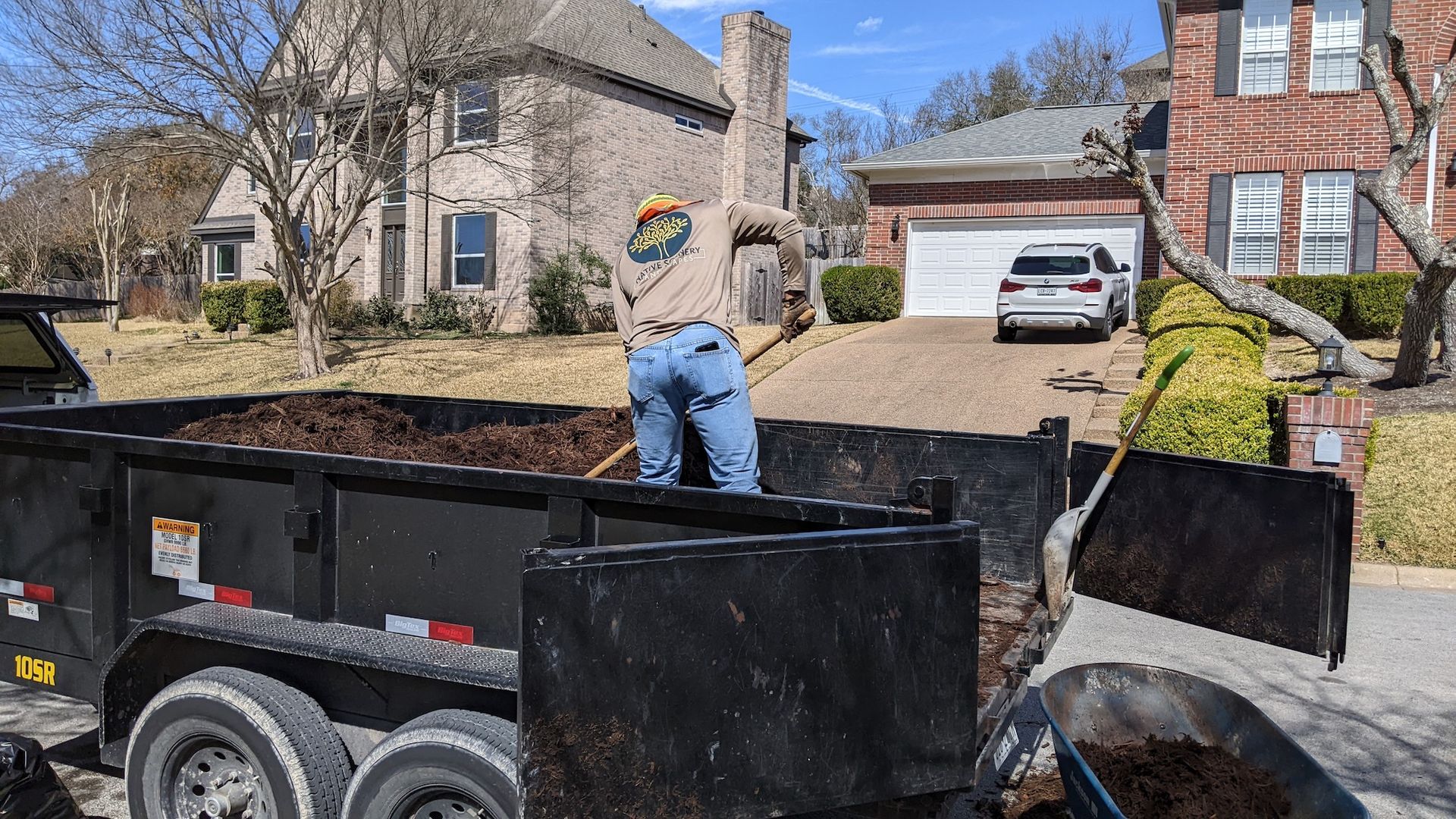 A man is digging in a dumpster in front of a house.