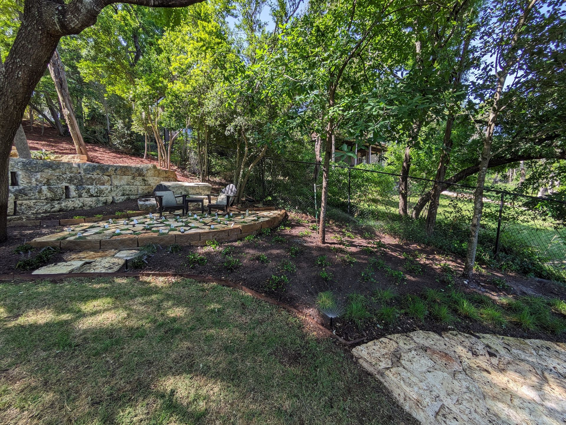 A backyard with a stone wall surrounded by trees and grass.