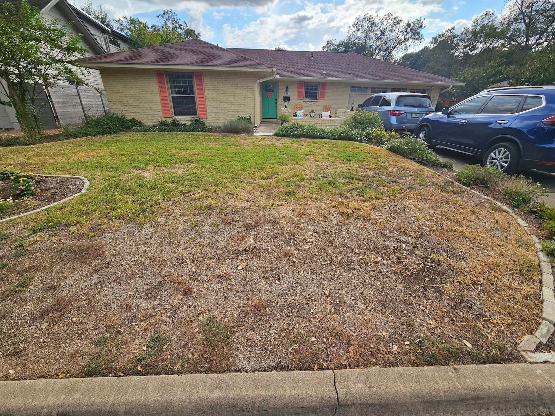 A house with a lush green lawn and a blue car parked in front of it.